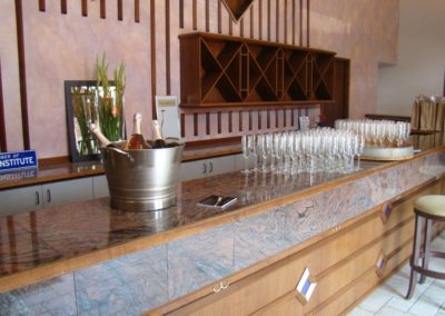 Tasting room bar with chiller bucket containing 3 bottles of sparkling wine, glasses stacked in formation.