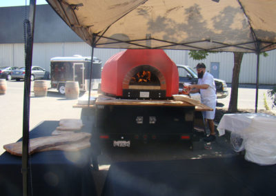 Dino Bucia, Chef of Diavola Restaurant preparing pizzas in front of a wood-fired oven in the parking lot of the Healdsburg facility at our Grand Opening in 2014.