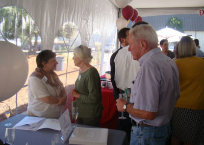 Grand Opening celebration party in 2014 with party guests holding glasses of sparkling wine and talking to each other in a tent.
