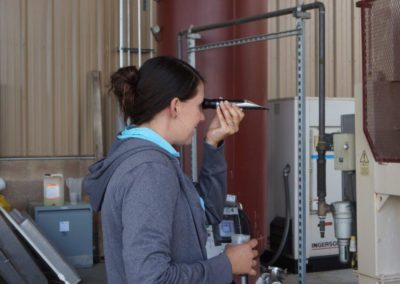 Client Winemaker Ashley Herzberg using a laboratory tool to check the sugar level of grapes on the crushpad at Rack & Riddle.