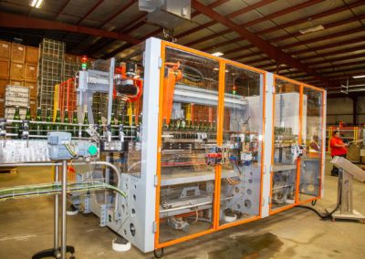 Full view of automated tirage bottling equipment. Machine operator is pictured in background.