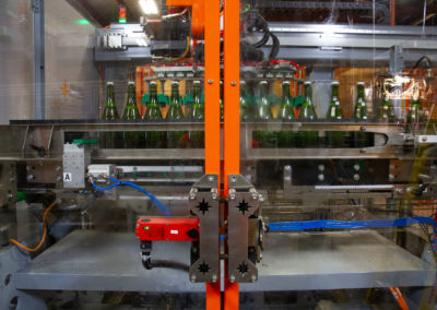 Glass doors in front of tirage bottling production line. Sparkling Wine bottles on the conveyer belt in the background.
