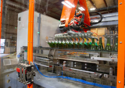 Sparkling wine bottles on the tirage bottling production line being removed from conveyer by robot arm.