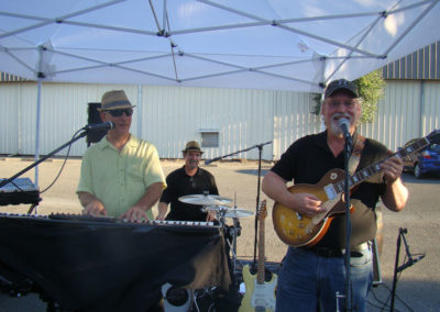 The Jim Milone Band playing music on instruments and singing at Rack & Riddle's 2014 Grand Opening party at the Healdsburg, Calfornia facility.