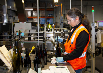 Wine lab worker testing wine directly in a bottle.