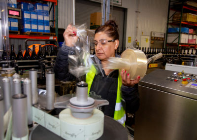 Production worker putting labels into automated production line equipment.